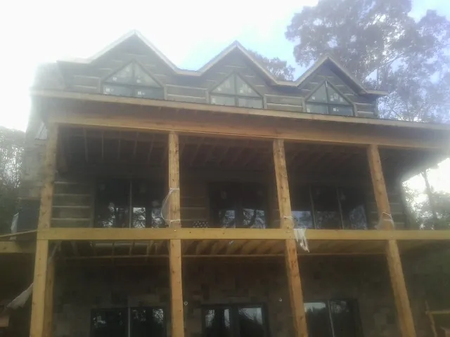 Dormers and porch framing on a large log home under construction — Roof Coating work by our crew in Harrisburg