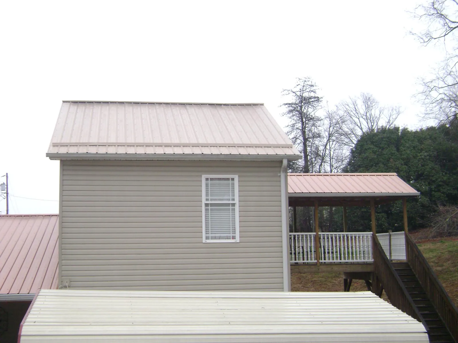 Tan metal roofs on a two story addition and attached porch, from a Roof Replacement job in Harrisburg